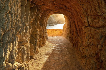 Path through a cave to sunrise over the sea