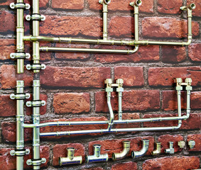 Fototapeta na wymiar Metal plumbing pipes on brick wall