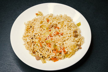 Instant noodles in white plate. Close-up.