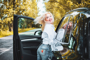 Young blonde attractive woman smiling and looking straight while driving a car