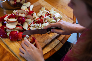 Young woman cutting apples with a big knife, as seen from above, point of view - High angle picture taken as part of an apple cider making workshop, in an indoors family environment
