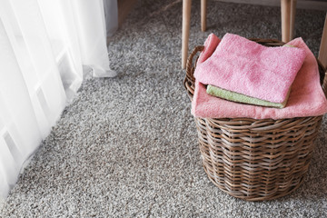 Wicker basket with folded clean towels on floor