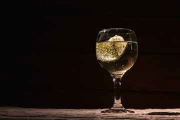 Alcohol is poured into a glass in which a slice of lemon with bubbles is lying