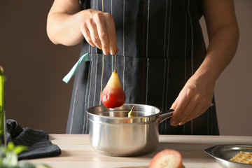 Woman preparing pear dessert with wine in kitchen