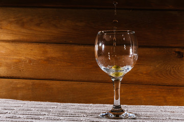 Champagne is poured into a glass, at the bottom of which is an olive