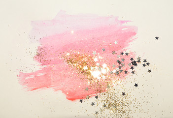 Golden glitter and glittering stars on abstract pink watercolor splash in vintage nostalgic colors.