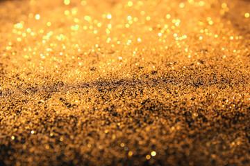 Golden glitters on dark background, closeup