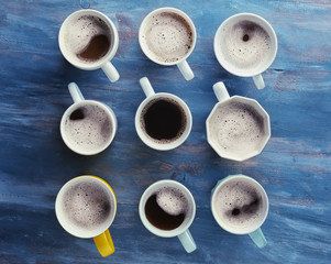 Many cups with tasty aromatic coffee on color wooden table, flat lay