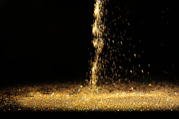 Sprinkling of golden glitters on dark background