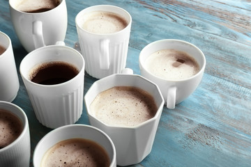 Many cups with tasty aromatic coffee on color wooden table
