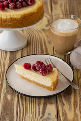 Piece of classic cheesecake with raspberries and coffee on a wooden background. Copy space.