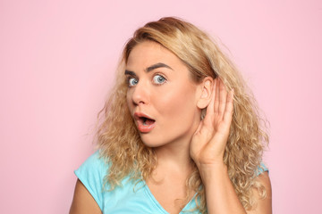 Naklejka premium Portrait of beautiful young woman trying to hear something on color background