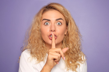 Naklejka premium Portrait of beautiful young woman showing silence gesture on color background