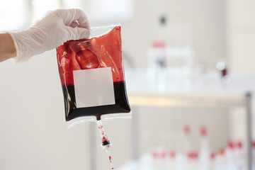 Hand in glove holding blood pack for transfusion in hospital