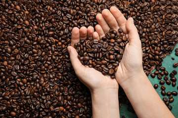 Woman holding roasted coffee beans, closeup