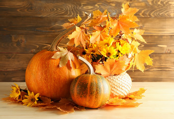 Fototapeta na wymiar Whole fresh pumpkins with autumn leaves on wooden table