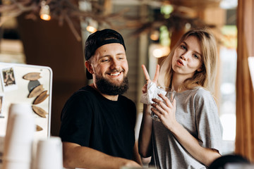 Two young smiling people.dressed in casual outfit, stand next to each other and smile to the camera in a cozy coffee shop.