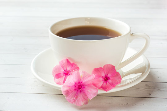 Fototapeta Cup of coffee on a white table and flowers of pink Phlox. The concept of morning Breakfast.