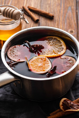 Mulled wine hot drink with citrus, apple and spices in aluminum casserole and Fir branch on background.
