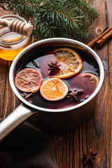Mulled wine hot drink with citrus, apple and spices in aluminum casserole and Fir branch on background.