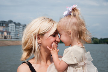 Mother and daughter are walking, having fun, playing in the park, on the banks of the river. Beautiful woman and little girl are walking in the summer outdoors. Concept family, love