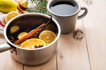 Mulled wine hot drink with citrus, apple and spices in aluminum casserole and Fir branch on background.