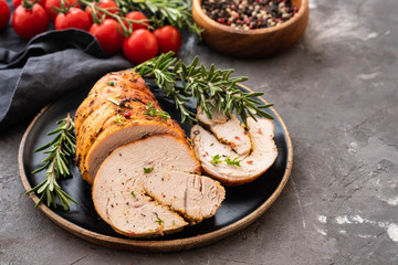 Stuffed turkey breast with baked vegetables and spices on a black background.