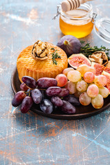 Cheese plate served with grapes, jam, figs, crackers and nuts on a background.