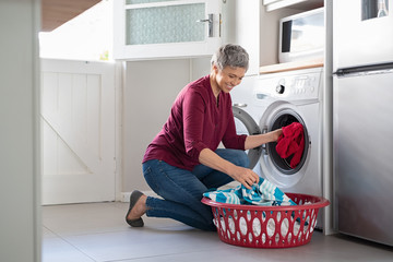 Woman loading clothes in washing machine