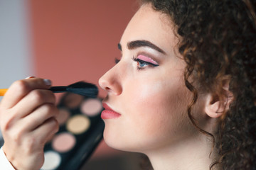 Obraz premium Closeup portrait of beautiful woman getting professional make-up with brush. Beauty and makeup concept