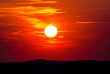 Beautiful colorful sunset with dramatic clouds and sun shining over mountains. Shot in Croatia.