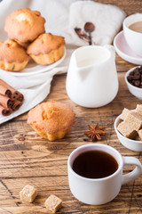 Breakfast and coffee for two persons, pastries, brown sugar and cinnamon with anise on a wooden background.