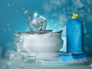 Clean dishes and cutlery on blue background with soap bubbles © laboko