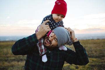 The dad holds his face in his arms. Family photo session at sunset.