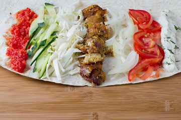 Ingredients for cooking shawarma lie on a pita bread. Middle Eastern dish to grill.