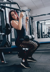 Fototapeta premium Beautiful athletic young woman making exercise at the gym. Young woman with muscular body.