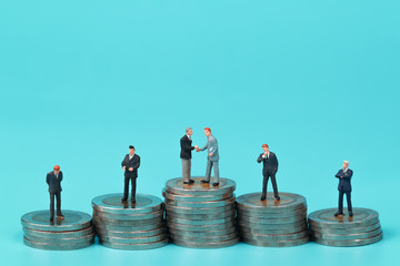 Miniature people: a group of businessman standing on coin stacking podium use as background