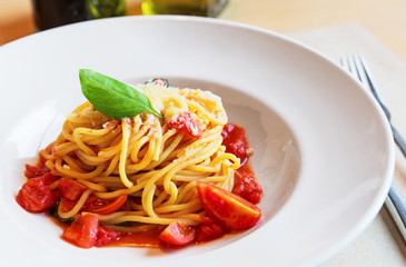 Spaghetti pasta with tomatoes and basil leaf on wooden table