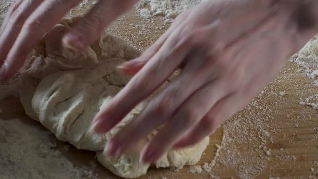 Baker kneading dough in flour on table. Scene. Man chef kneads the dough. Hands knead dough on a table in kitchen close up