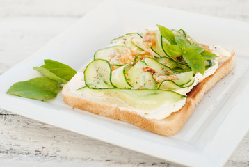 Sandwiches with cheese and cucumber slices, basil leaves, on wood. Healthy snack food concept