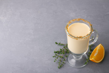 Obraz na płótnie Canvas Homemade eggnog with thyme and orange in a glass on a gray background, free space. Traditional winter Christmas drink