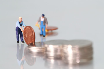 Miniature people: worker with coins, business concept using as background