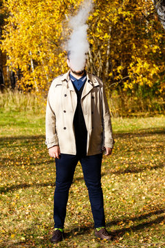 Man with exploding smoking head in colorful autumn forest