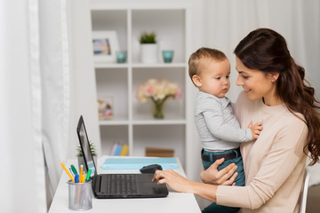motherhood, multi-tasking, family and people concept - happy mother with baby and laptop working at home