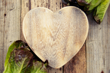 Lettuce leaves on cutting board heart shape, on wooden background. Preparation of salad and healthy food. Lettuce cabbage. Copy space.