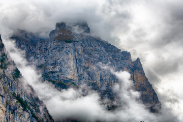 Fototapeta na wymiar Wengwald cliff Lauterbrunnen Swiss in steel-blue contrast surrounded by mystic clouds