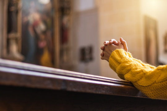 Christian woman is praying with hands crossed in church 