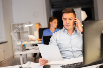 Fototapeta premium business, deadline and technology concept - man with computer calling on smartphone late at night office