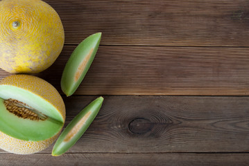 Cantaloupe yellow fresh melon isolated with sliced melon, wooden table, gray background. Summer fruits. Copy space.