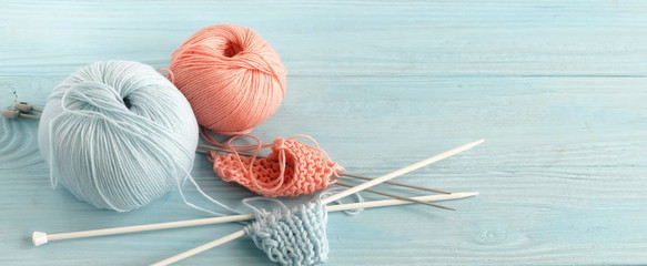 Knitting wool and knitting needles in pastel blue and pink colors on blue  wooden background. top...